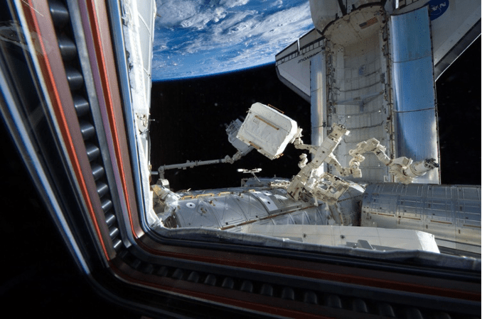 Figure 22 - Il trasferimento di AMS-02, tramite il Canadarm-2, durante la missione STS-134 dello shuttle Endeavour (che si vede agganciato alla ISS) (2011). Cr: US National Archives