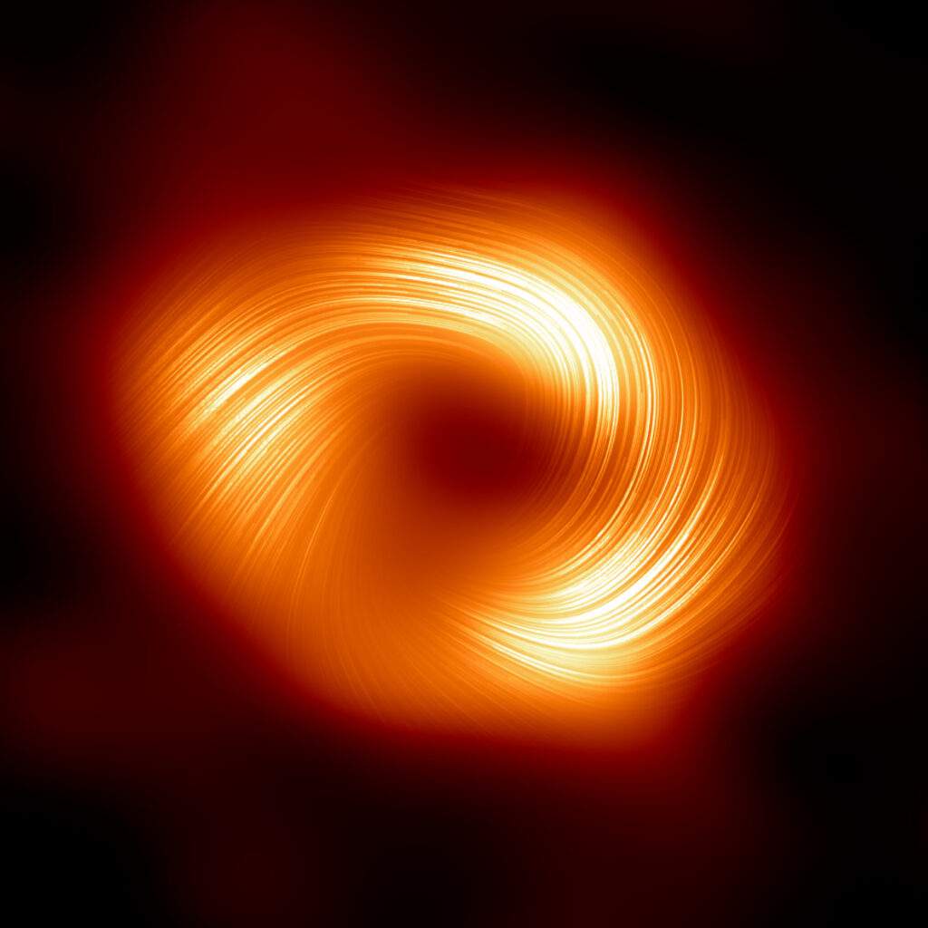 La prima immagine di Sagittarius A*, il buco nero supermassiccio al centro della Via Lattea, in luce polarizzata. Le linee sovrapposte all'immagine indicano l’orientamento della polarizzazione, legata al campo magnetico che circonda la zona. Credits: EHT Collaboration