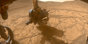 Immagine del rover Perseverance della NASA mentre raccoglie dati su "Walhalla Glades", scattata nella regione Bright Angel del cratere Jezero da una delle telecamere anteriori. La telecamera WATSON sullo strumento SHERLOC, tornato operativo, è la più vicina alla superficie marziata. Credits: NASA/JPL-Caltech